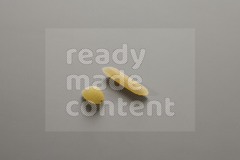 Shells pasta with other types of pasta on grey background