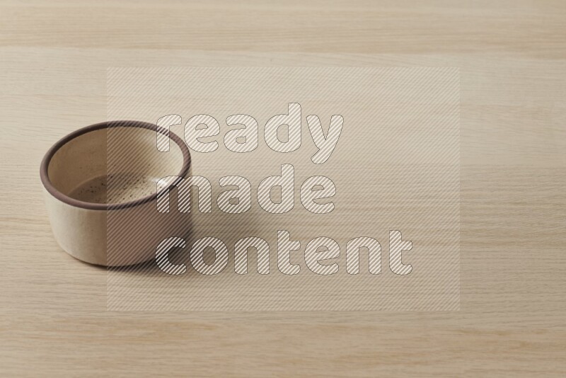 A beige pottery oven bowl on light wooden background