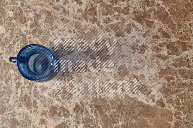 A colored glass jug on beige marble background