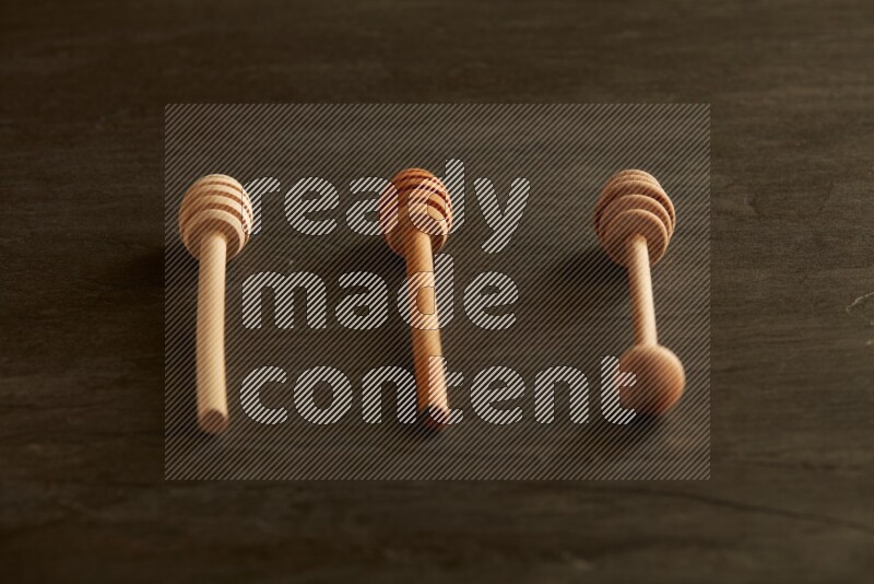 Wooden honey dipper on black slate background
