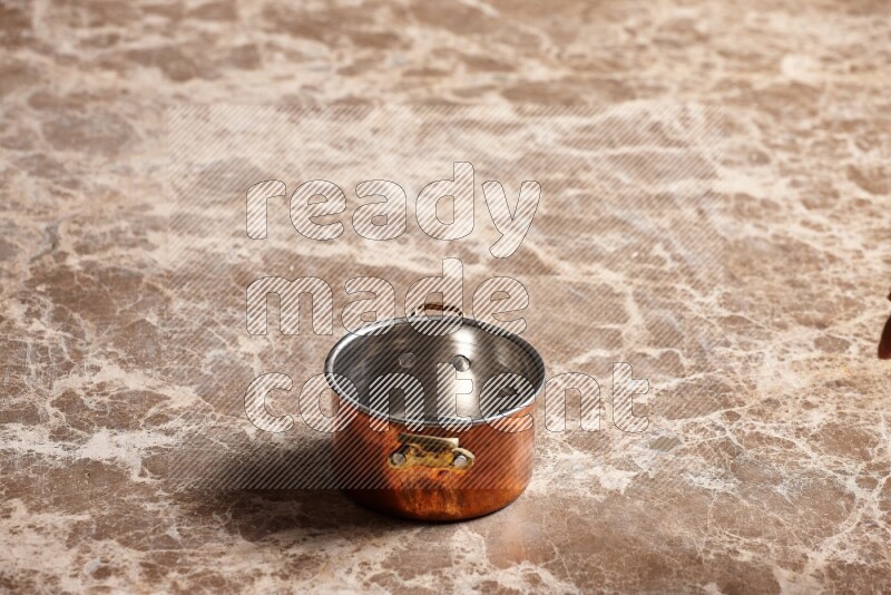 A small copper pot on beige marble background