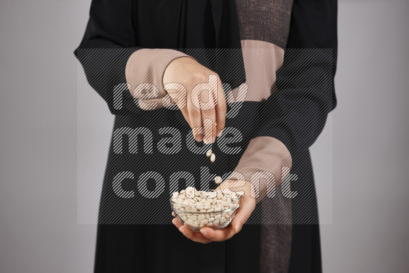 Woman in abaya holding different kinds of legumes in different positions