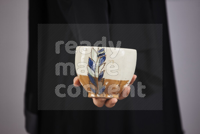 A woman in black abaya holding different pottery essentials in different positions