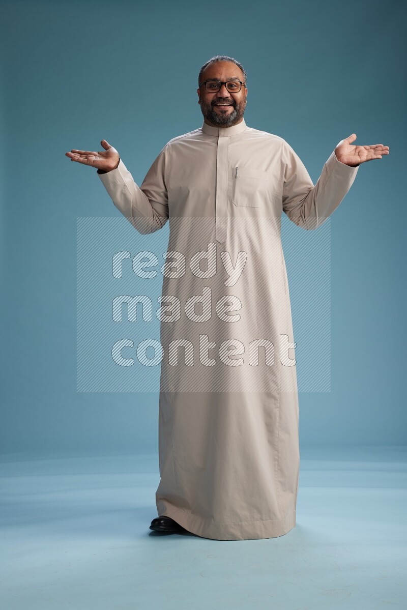Saudi Man without shimag Standing Interacting with the camera on blue background