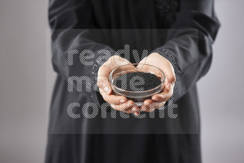 Woman in abaya holding different kinds of spices in different positions