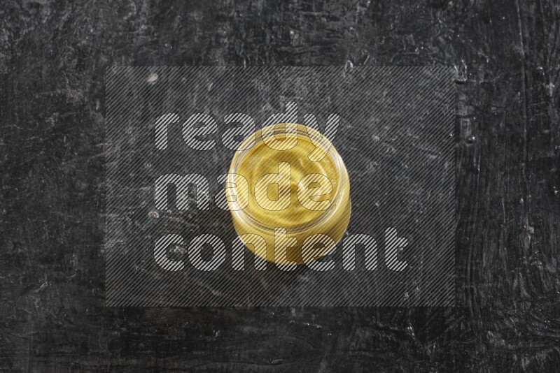 وعاء زجاجي ممتلئ بمعجون الخردل على خلفية سوداء