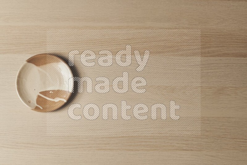 صحن فخاري متعدد الألوان على خلفية خشبية فاتحة