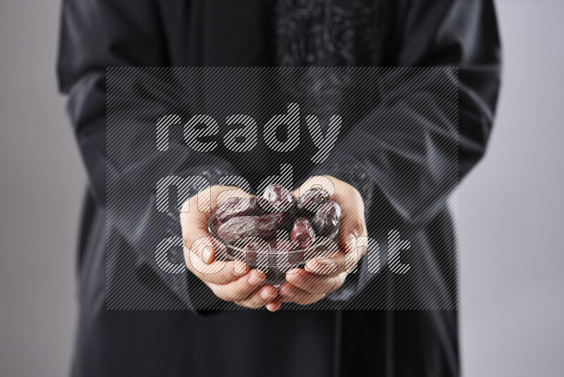 Woman in abaya holding dates in different positions