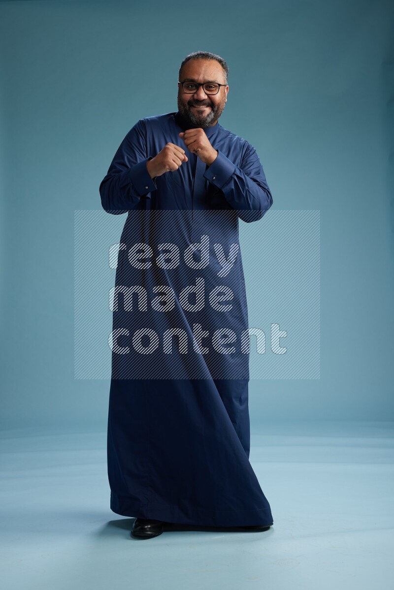 Saudi Man without shimag Standing Interacting with the camera on blue background