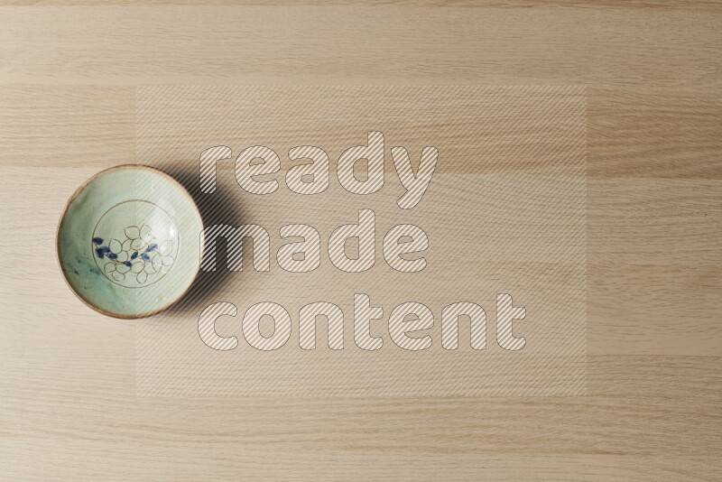 A decorative pottery plate on light wooden background