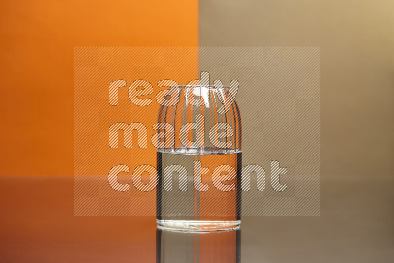 The image features a clear glassware filled with water, set against orange and beige background
