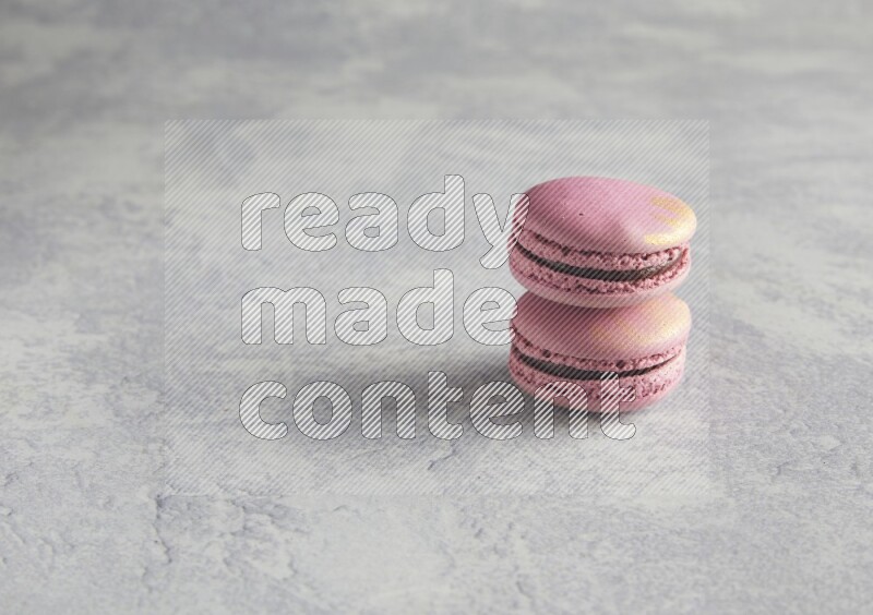 45º Shot of two Purple Strawberry macarons on white  marble background