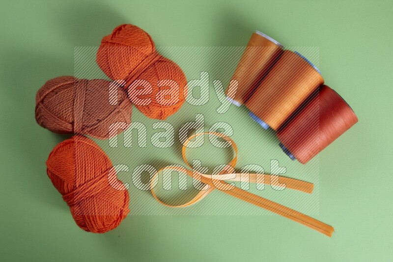 An orange collection of sewing and tailoring tools arranged on a green background