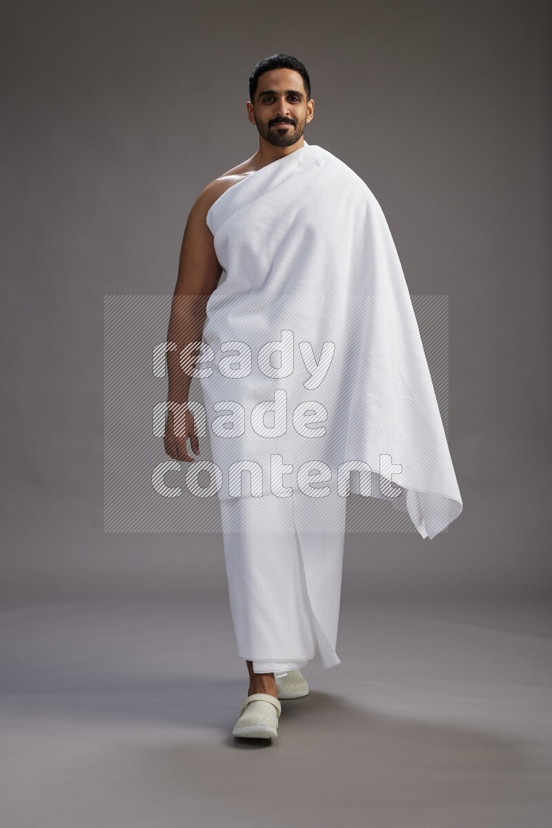 A man wearing Ehram Standing Interacting with the camera on gray background