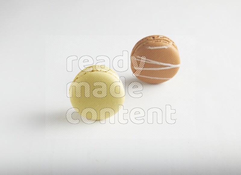 45º Shot of of two assorted Brown Irish Cream, and Yellow Lime macarons on white background