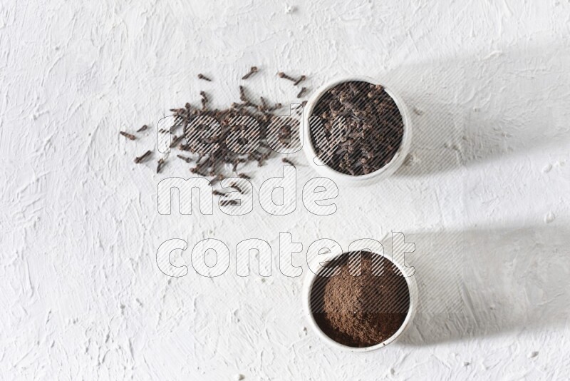 وعاءين من السيراميك بيج اللون، أحدهما مملوء بالقرنفل والآخر مملوء بالبودرة على أرضية بيضاء