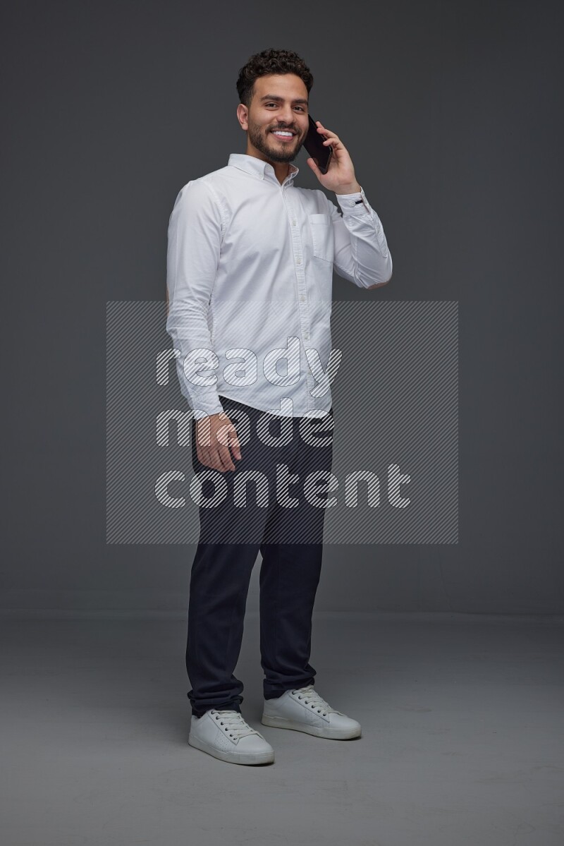 A man wearing smart casual talking in the phone eye level on a gray background