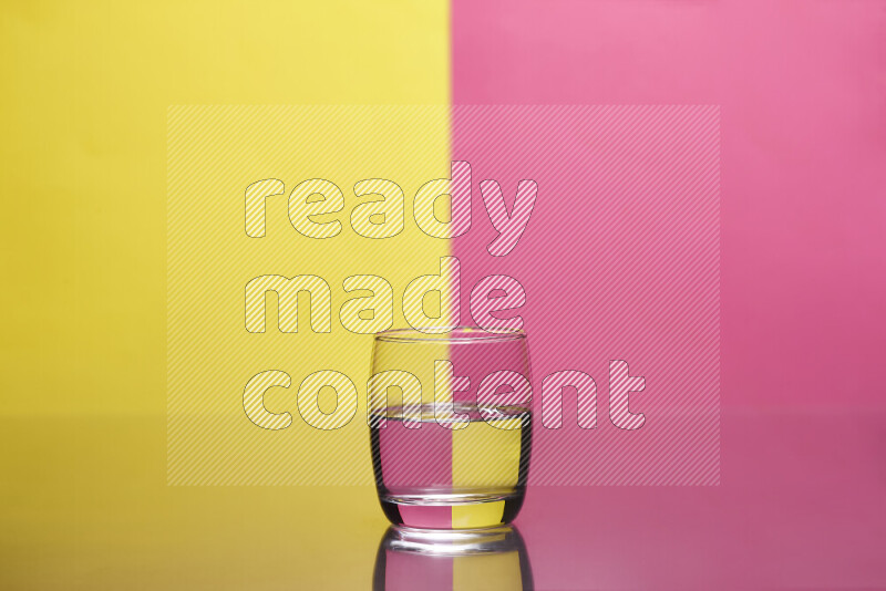 The image features a clear glassware filled with water, set against yellow and pink background