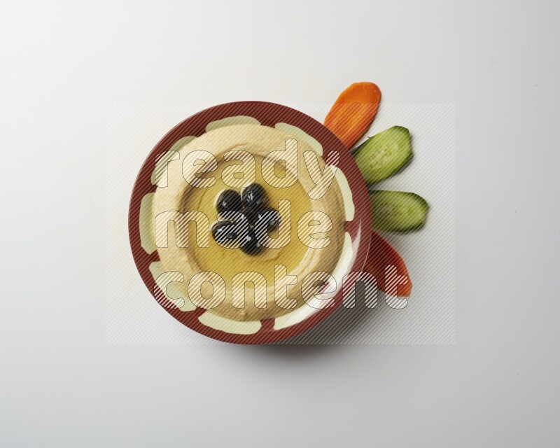 Hummus in a traditional plate garnished with black olives on a white background