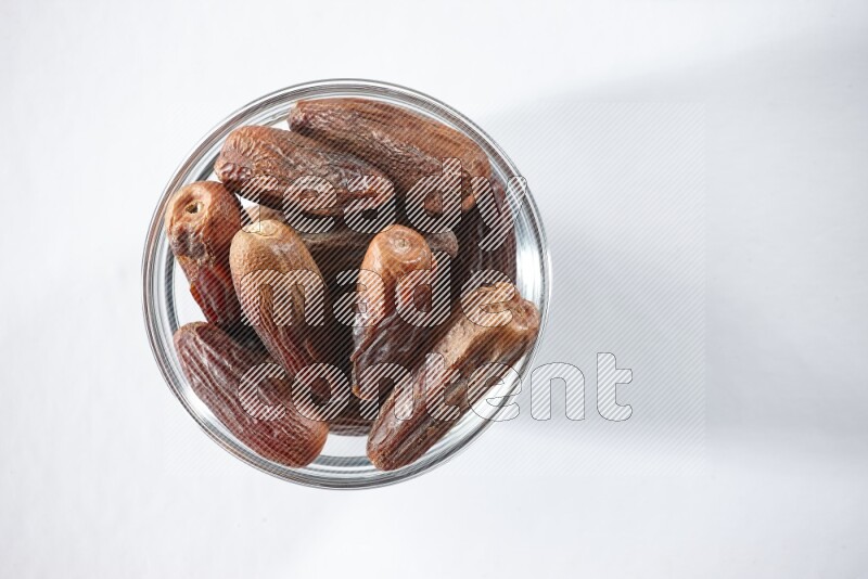 A glass bowl full of dried dates on a white background in different angles