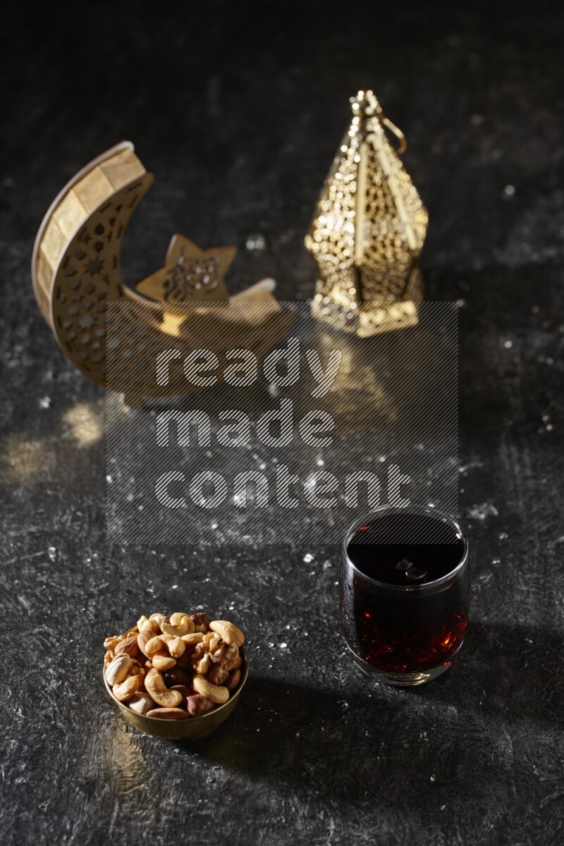 مكسرات في وعاء معدني مع مشروب التمر الهندي بجانب فوانيس ذهبية علي خلفية سوداء