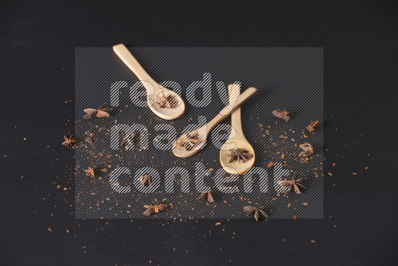 Star Anise in wooden spoons on black flooring