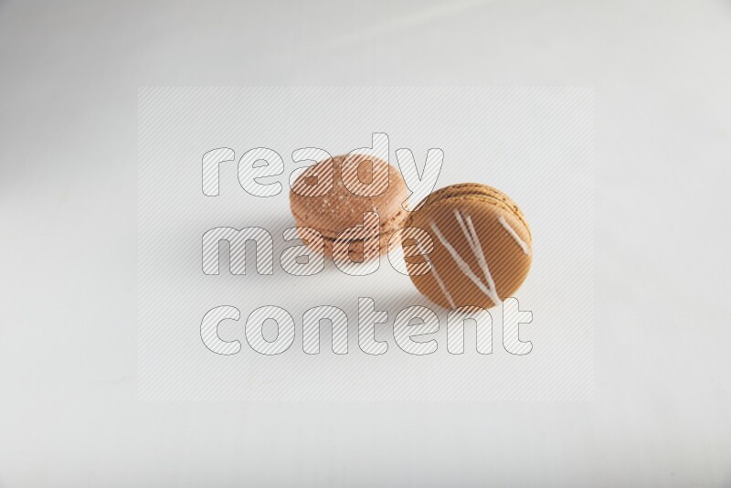45º Shot of of two assorted Brown Irish Cream, and Brown Hazelnuts macarons on white background