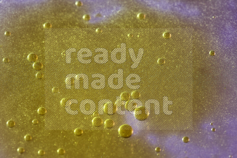 لقطات مقربة لقطرات ألوان مائية صفراء على سطح الزيت على خلفية وردية