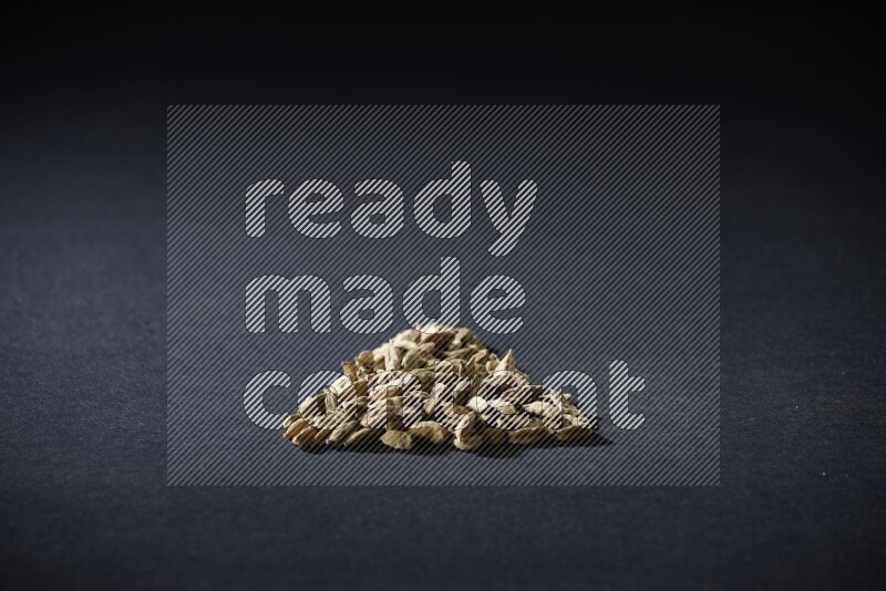 Cardamom in a triangle shape on black flooring