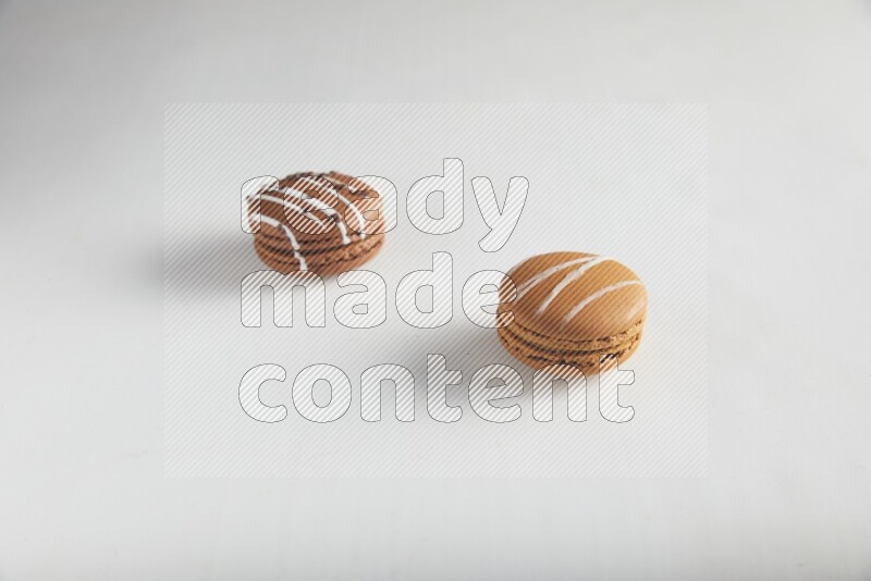 45º Shot of of two assorted Brown Irish Cream, and Brown white Chocolate Caramel macarons on white background