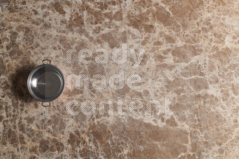 A small copper pot on beige marble background