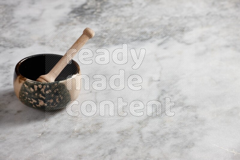 Multicolored pottery bowl with wooden honey dipper in it on grey marble background