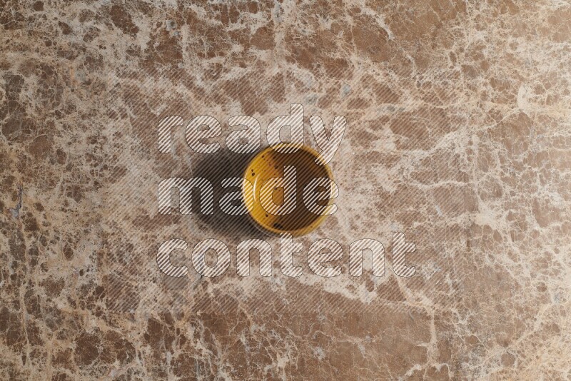 A multicolored pottery bowl on beige marble background